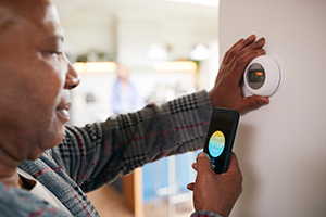 Person looking at smart thermostat and app on phone