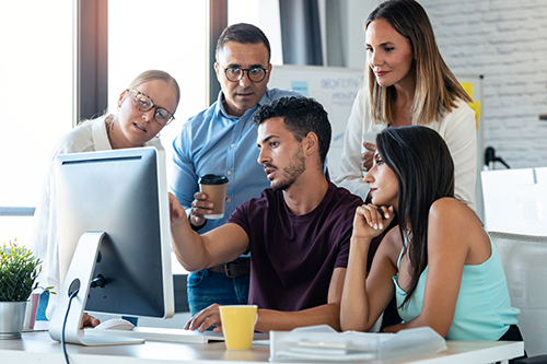 Ocean County website designer at desk surrounded by coworkers planning a new site